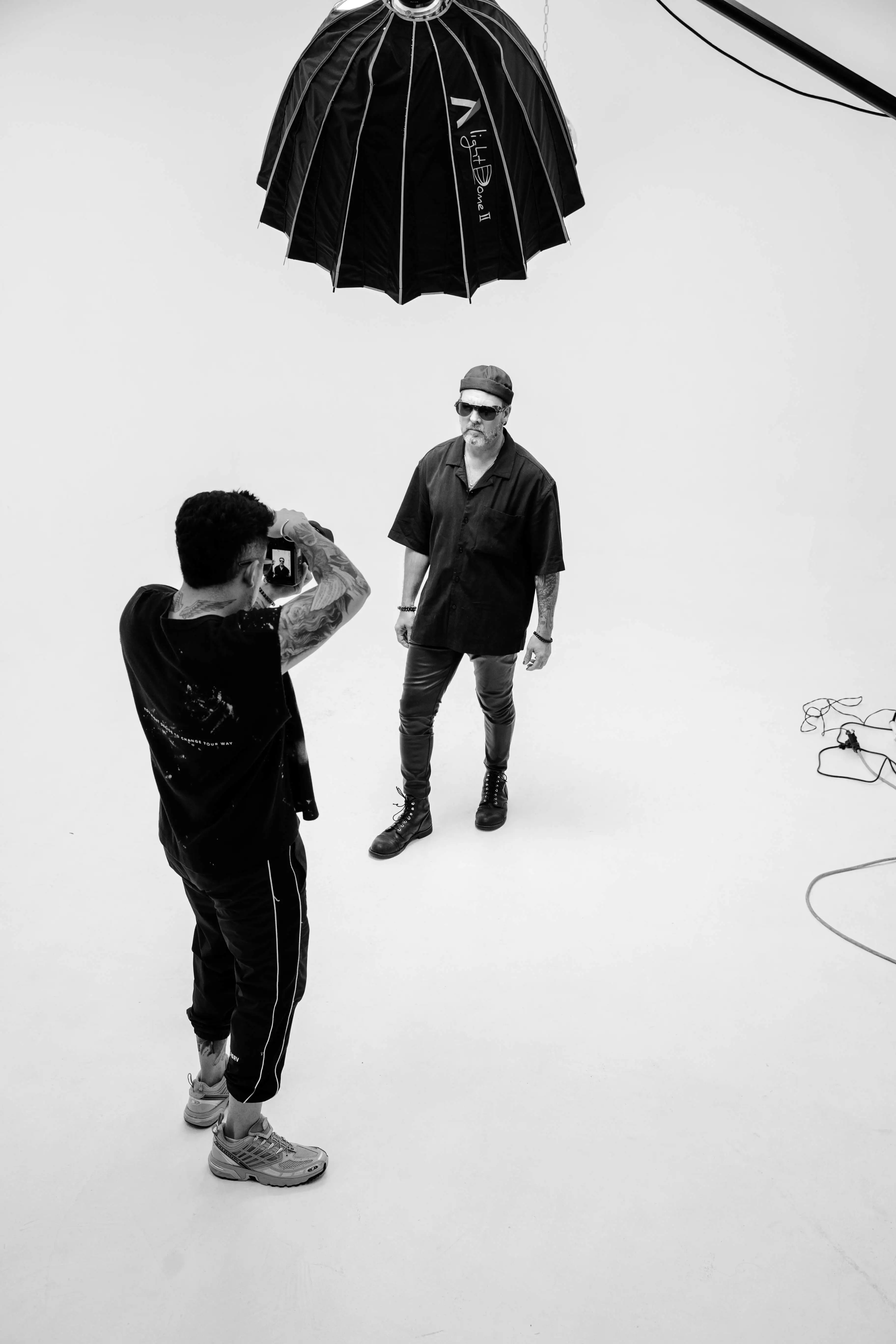 Male photographer with tattoos taking a portrait photo of a male client in a studio
